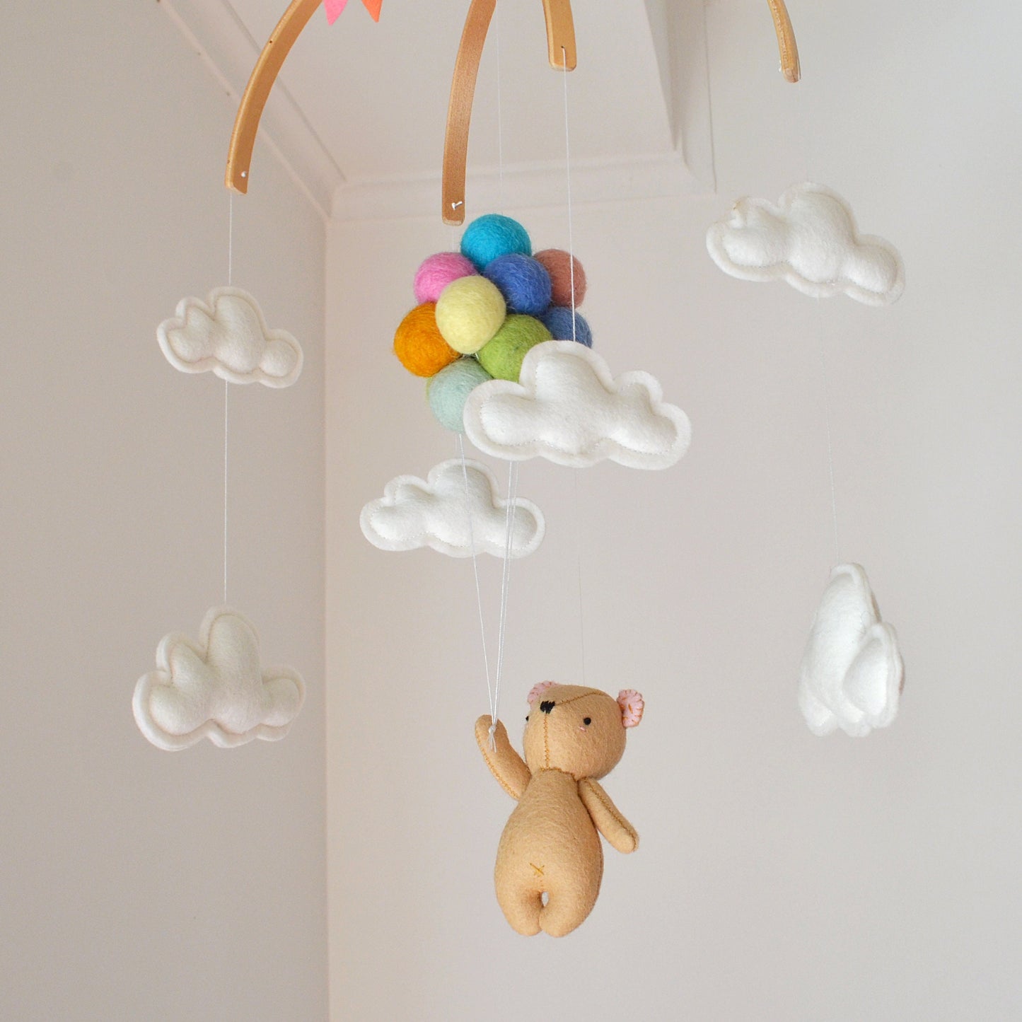 Teddy bear flying with pastel rainbow balloons