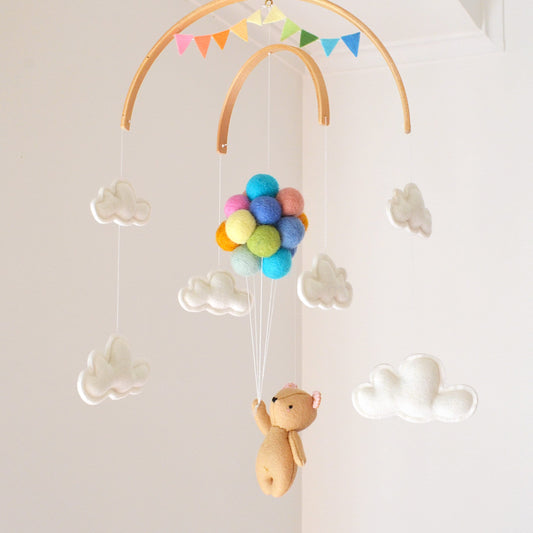 Teddy bear flying with pastel rainbow balloons