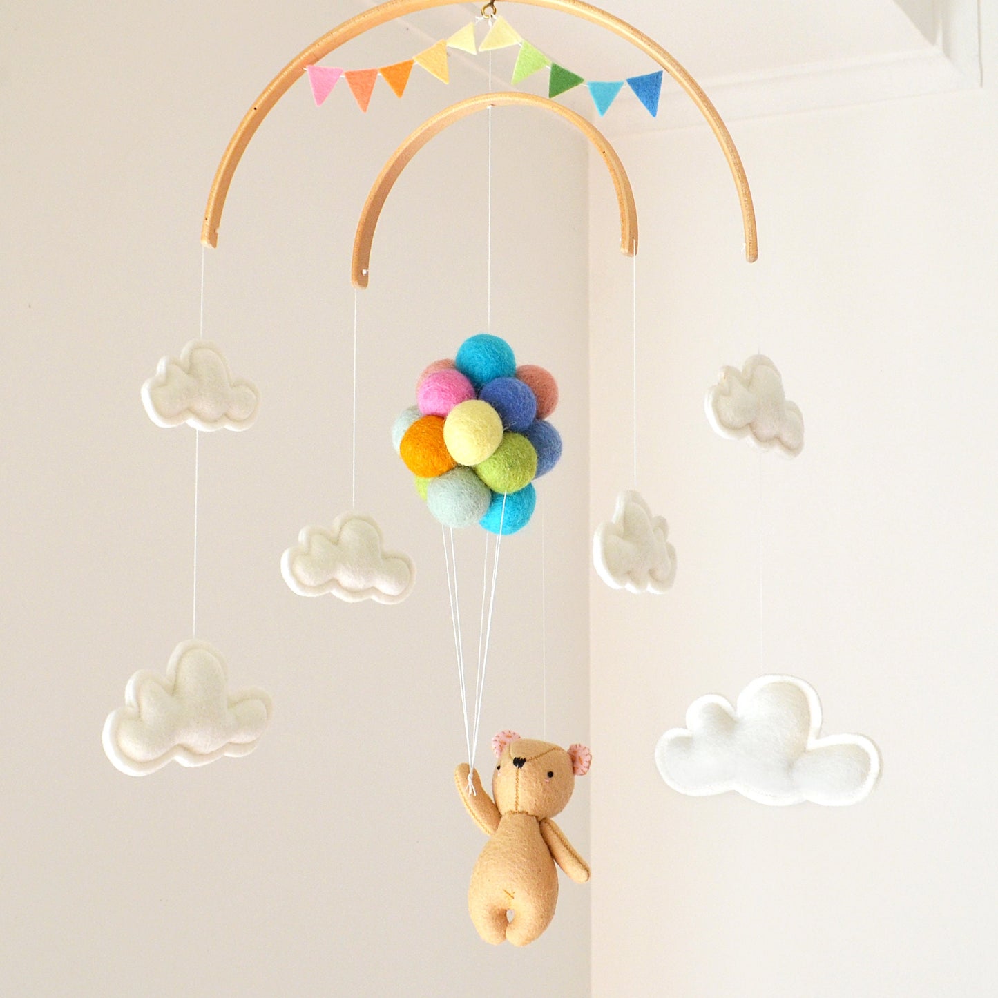 Teddy bear flying with pastel rainbow balloons